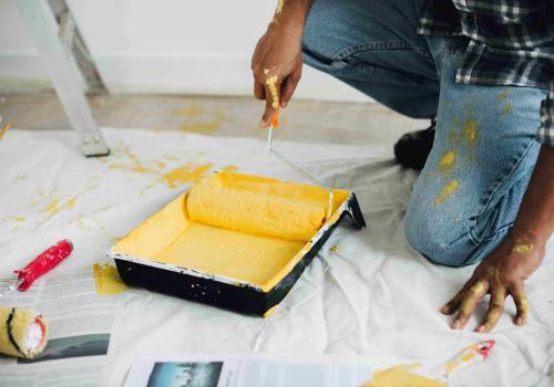 homme qui met de la peinture jaune sur son rouleau pour peindre un mur - credit photo freepik