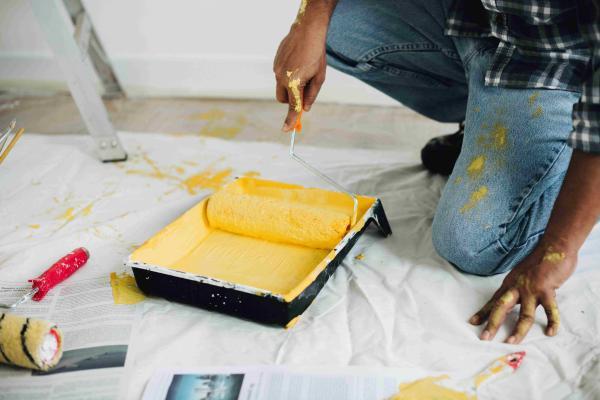 homme qui met de la peinture jaune sur son rouleau pour peindre un mur - credit photo freepik